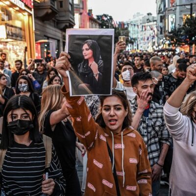 Manifestante marcha pela avenida Istiklal, em Istambul, enquanto segura um retrato de Mahsa Amini durante ato em apoio à jovem iraniana que morreu após ser presa em Teerã