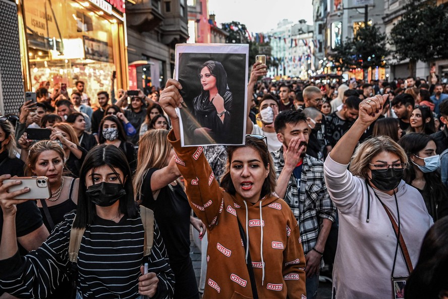Manifestante marcha pela avenida Istiklal, em Istambul, enquanto segura um retrato de Mahsa Amini durante ato em apoio à jovem iraniana que morreu após ser presa em Teerã