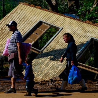 Pessoas passam por uma casa danificada por um ciclone em Muçum, Rio Grande do Sul