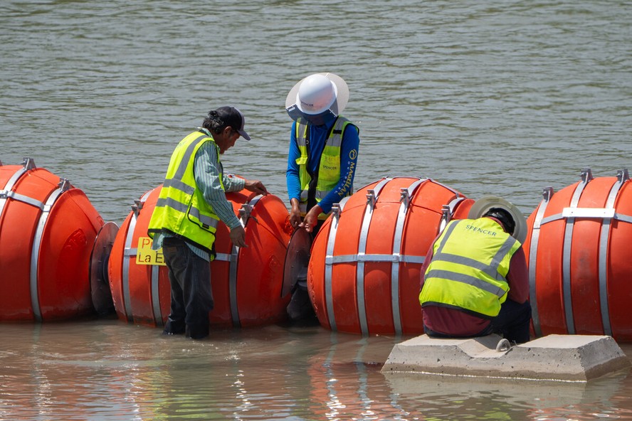 Trabalhadores fazem manutenção nas boias antimigrantes colocadas ao longo da fronteira do Rio Grande no Texas