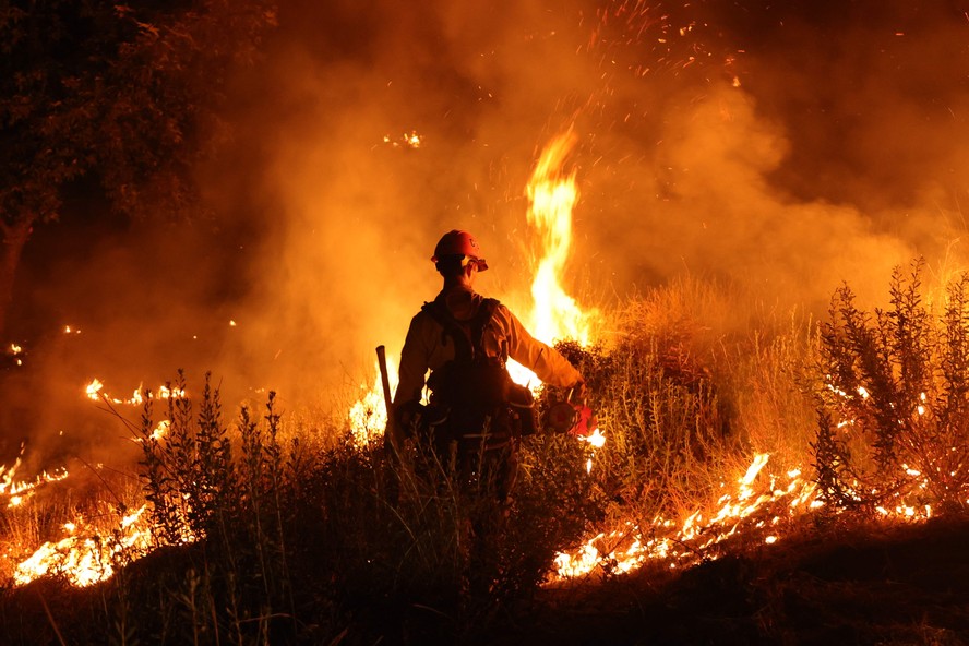 Um bombeiro tenta controlar o 'Rabbit Fire', que queimou mais de 7.500 acres em Moreno Valley, no Riverside County, Califórnia. Temperaturas brutalmente altas ameaçaram dezenas de milhões de americanos em julho, enquanto várias cidades se preparavam para quebrar recordes sob uma cúpula de calor implacável que assou partes do país durante toda a semana.