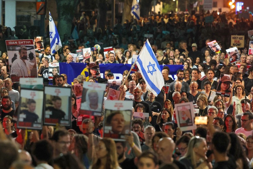 Pessoas carregam pôsteres e gritam palavras de ordem durante manifestação em Tel Aviv pela libertação das pessoas feitas reféns pelo Hamas