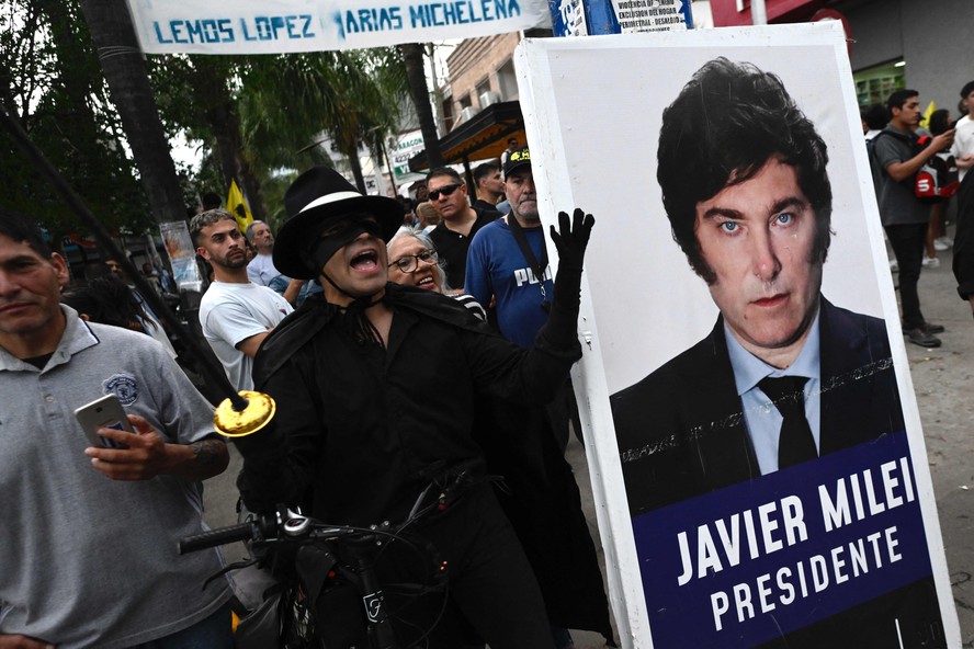 Apoiador segura cartaz de Javier Milei durante evento de campanha em Ezeiza, na Grande Buenos Aires