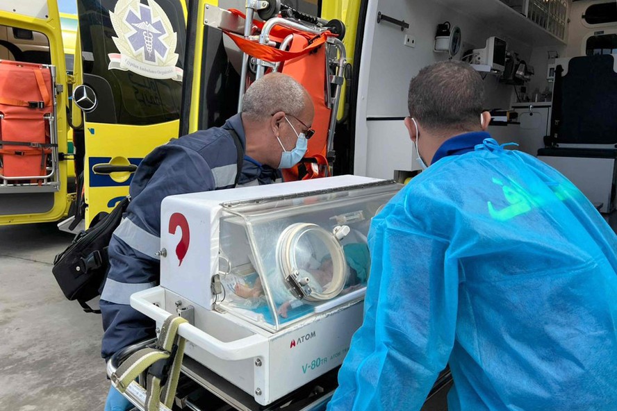 Médicos egípcios transportam bebê palestino prematuro evacuado de Gaza para uma ambulância
