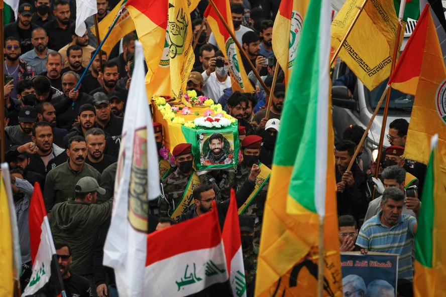 Pessoas em luto no Iraque carregam o caixão de um combatente durante funeral em Bagdá