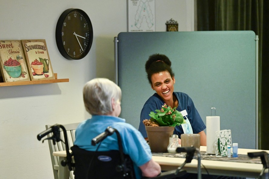 Mulher idosa interna de uma casa de repouso em Broby, na Suécia, conversa com uma funcionária