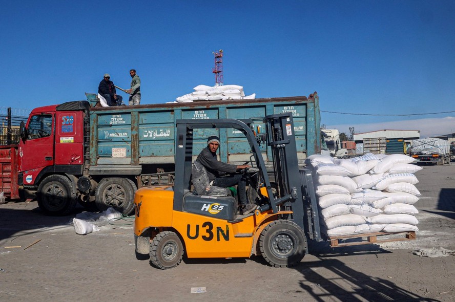 Trabalhador palestino organiza caixas de ajuda humanitária que entraram em Gaza pela passagem de Kerem Shalom, na parte sul do território palestino