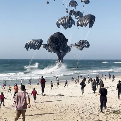 Moradores de Gaza correm em direção ao Mar Vermelho para buscar ajuda humanitária enviada por paraquedas
