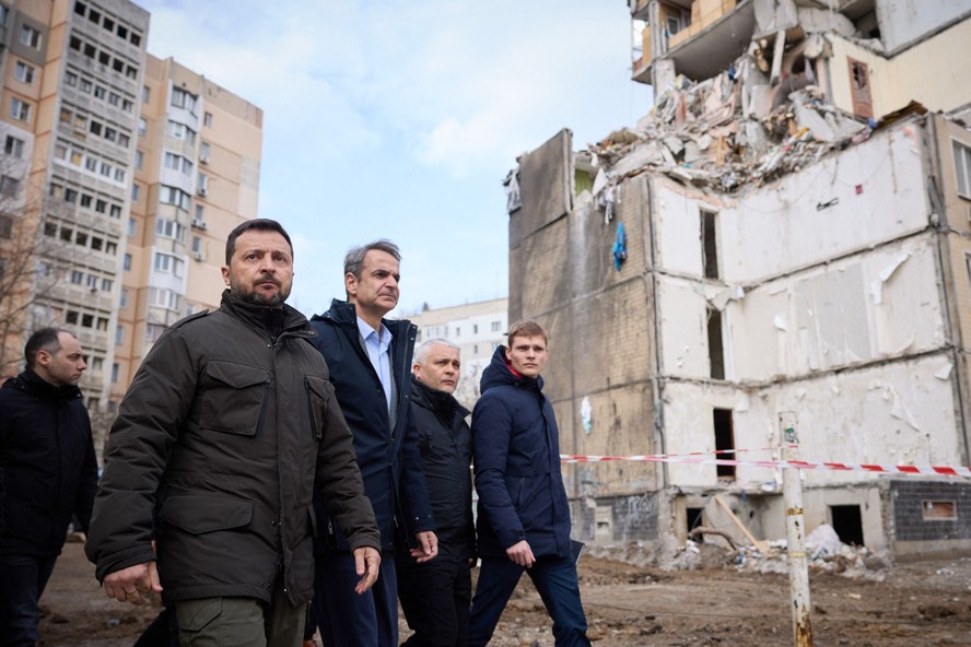 Presidente da Ucrânia, Volodymyr Zelensky (E) e premier da Grécia, Kyriakos Mitsotakis (C) caminham por área residencial destruída de Odessa