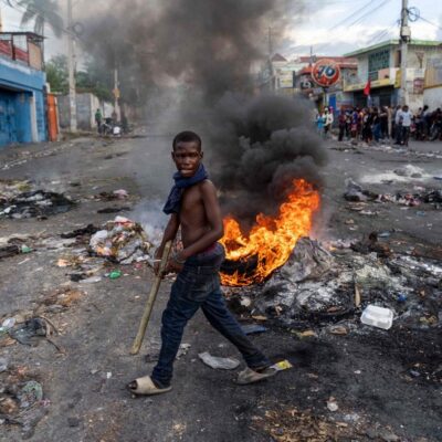 Homem caminha em frente a barricada durante protesto contra o então premier do Haiti, Ariel Henry, em Porto Príncipe