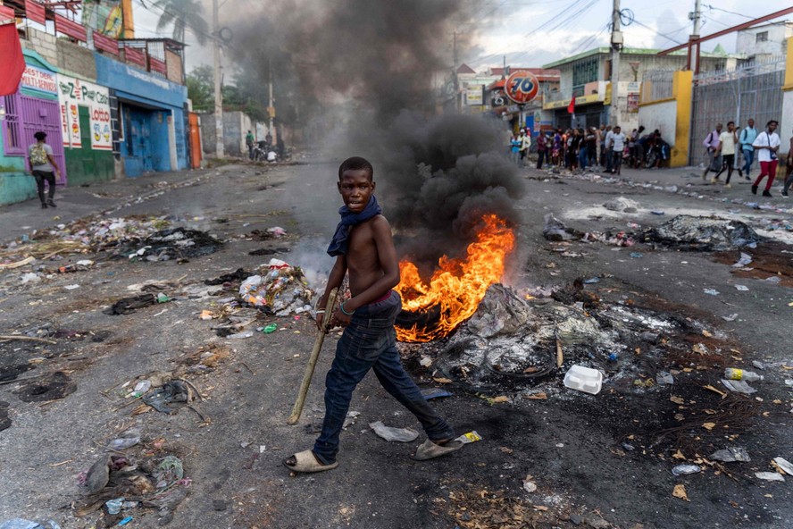 Homem caminha em frente a barricada durante protesto contra o então premier do Haiti, Ariel Henry, em Porto Príncipe
