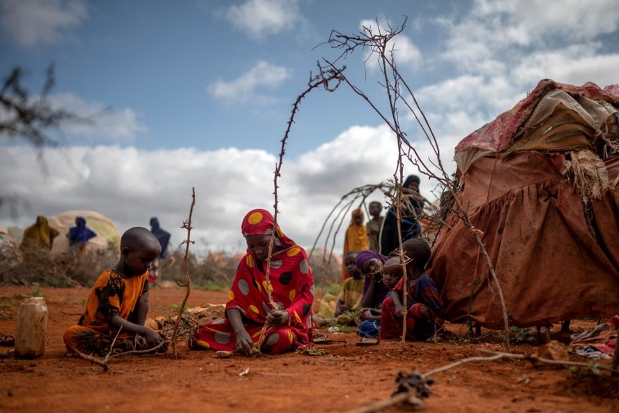 Menina e sua sobrinha construindo uma tenda com galhos em Baidoa, na Somália, onde dezenas de milhares de pessoas se deslocaram para fugir da fome e da seca