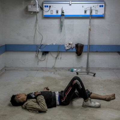 Jovem palestino ferido em bombardeio israelense deita-se no chão enquanto aguarda atendimento médico no hospital al-Shifa, na Cidade de Gaza
