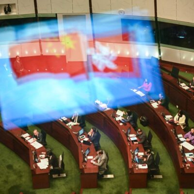 Bandeiras da China e de Hong Kong refletidas em vidro do plenário do Parlamento