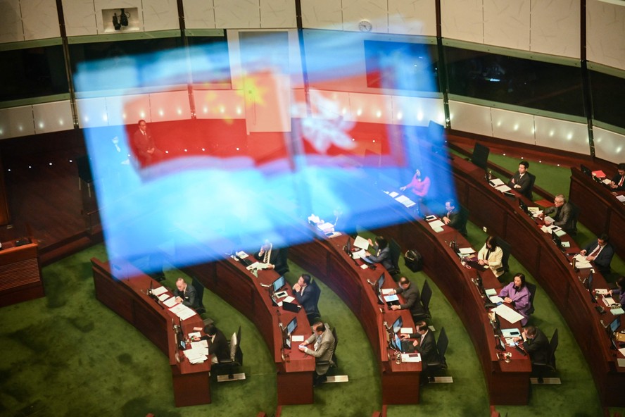 Bandeiras da China e de Hong Kong refletidas em vidro do plenário do Parlamento