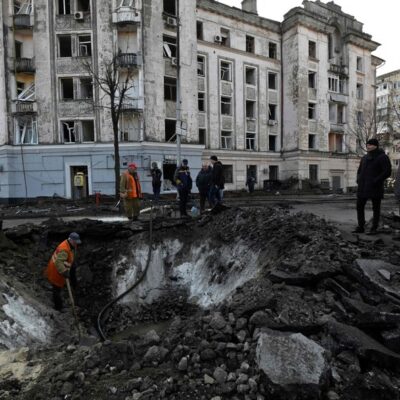 Trabalhadores dos serviços municipais ucranianos examinam e reparam os danos após um ataque com mísseis em Kiev