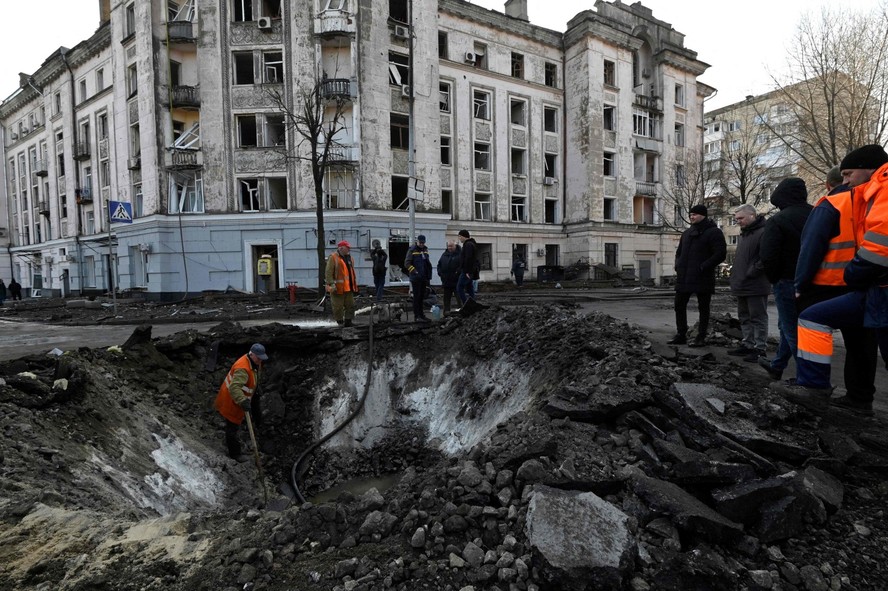 Trabalhadores dos serviços municipais ucranianos examinam e reparam os danos após um ataque com mísseis em Kiev