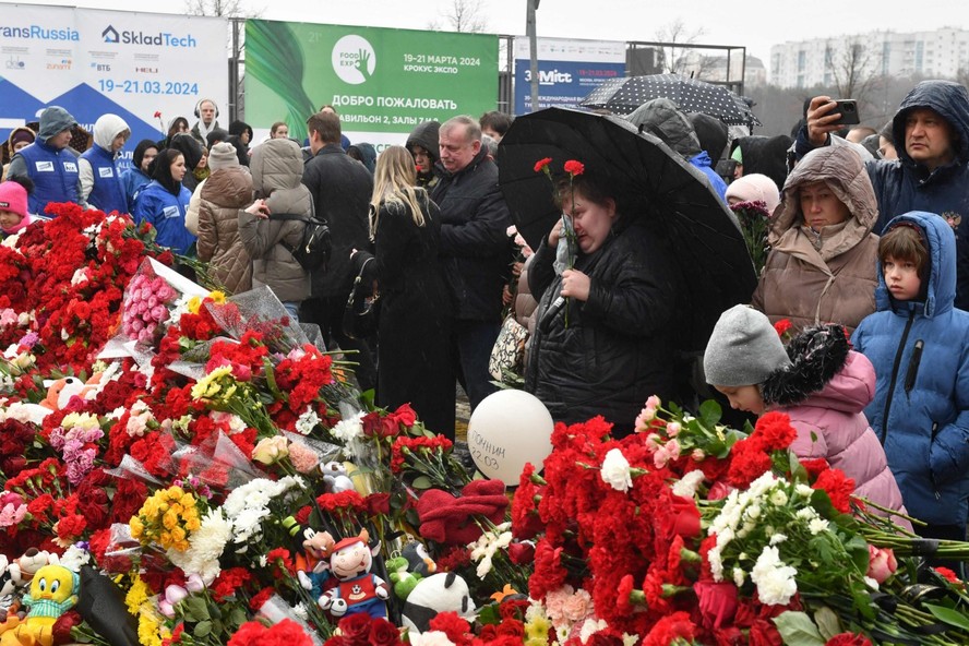 Pessoas depositam flores em um memorial improvisado em frente à prefeitura de Crocus, em Krasnogorsk