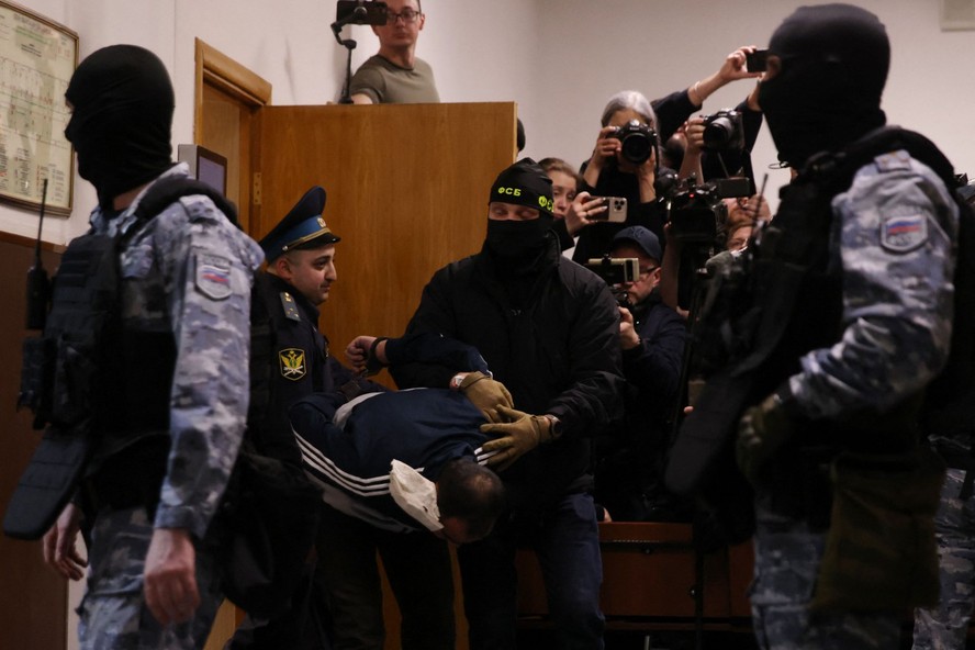 Um dos acusados do ataque terrorista na Rússia sendo segurado por policiais