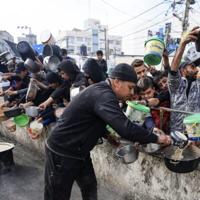 Palestinos coletam alimentos em um ponto de doação em um campo de refugiados em Rafah, no sul da Faixa de Gaza, em 23 de dezembro de 2023, em meio a contínuas batalhas entre Israel e o grupo militante Hamas