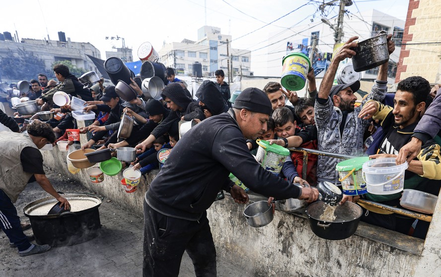 Palestinos coletam alimentos em um ponto de doação em um campo de refugiados em Rafah, no sul da Faixa de Gaza, em 23 de dezembro de 2023, em meio a contínuas batalhas entre Israel e o grupo militante Hamas