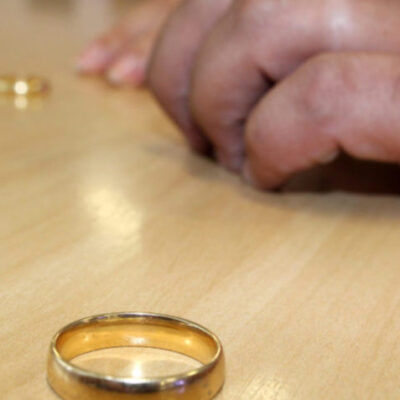 Alianças de ouro em uma mesa, afastadas uma da oura e a mão de um homem