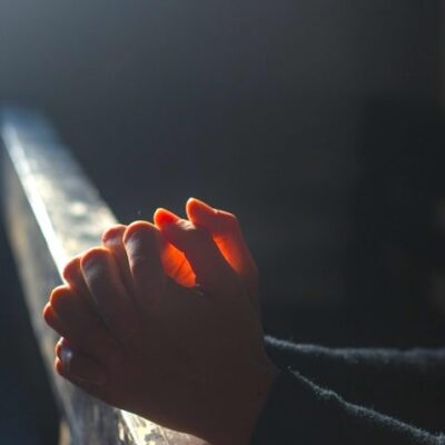 Mãos juntas orando em uma igreja
