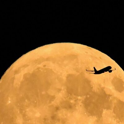 Um Airbus A320 se preparando para pousar na Inglaterra, sobrevoa a lua cheia nascendo no céu de Londres