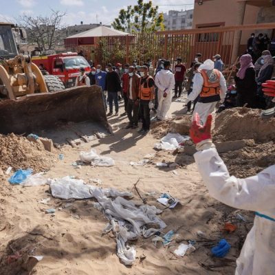 Profissionais de saúde palestinos procuram corpos enterrados no complexo do hospital Nasser em Khan Yunis, no sul da Faixa de Gaza.