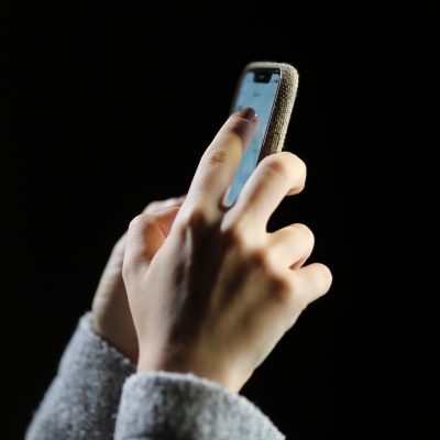 Mão toca celular com touch screen em fundo preto