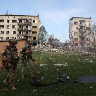 Oficiais de força policial especial caminham em frente a apartamentos destruídos por bombas aéreas durante a evacuação de moradores da vila de Ocheretine, não muito longe de Avdiivka, em Donetsk