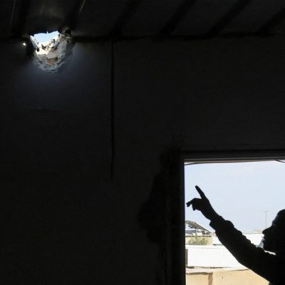 Um parente aponta para um buraco no telhado de um prédio causado por um projétil que feriu a menina beduína Amina, de sete anos, em sua aldeia, não reconhecida pelas autoridades israelenses, no deserto do sul de Negev.