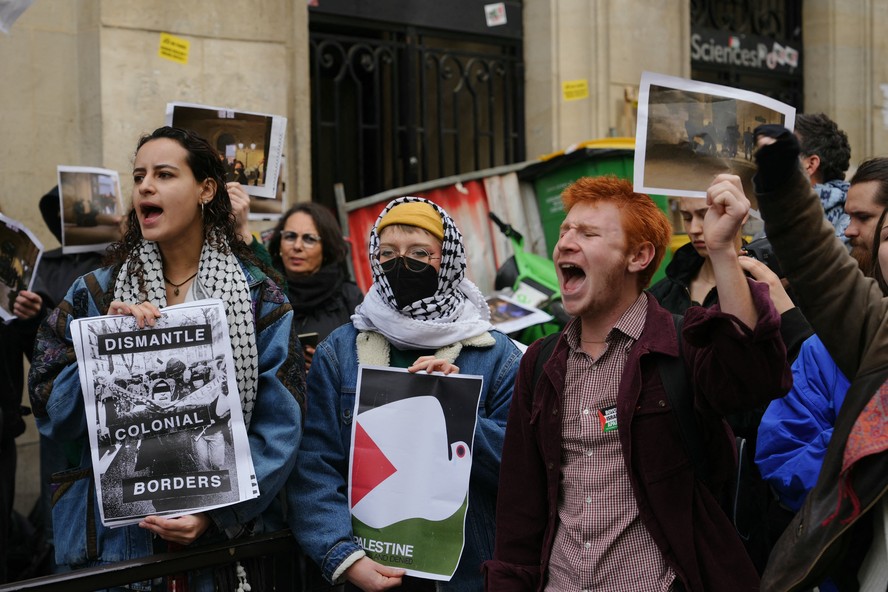 Manifestantes seguram cartazes com os dizeres 'desmantelar fronteiras coloniais' enquanto estudantes ocupam um prédio do Instituto de Estudos Políticos em apoio aos palestinos, em Paris.