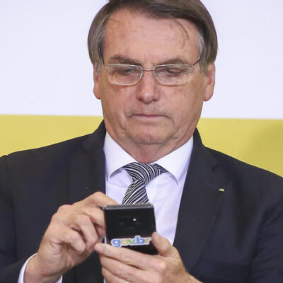 Presidente da República, Jair Bolsonaro, mexendo no celular durante evento no Planalto