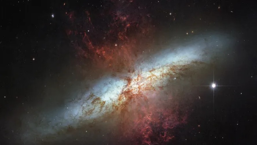 Observações do Telescópio Hubble da gloriosa galáxia M82, repleta de luz estelar branca e nuvens de gás vermelhas. As estrelas estão se formando 10 vezes mais rápido aqui do que na Via Láctea, de acordo com a NASA.