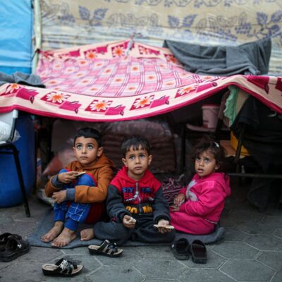 Crianças olham para o céu em um acampamento administrado pelas Nações Unidas para palestinos deslocados em Khan Younis, no sul da Faixa de Gaza