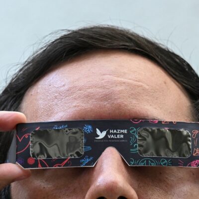 Homem testa os óculos de sol especiais para observar o próximo eclipse solar.