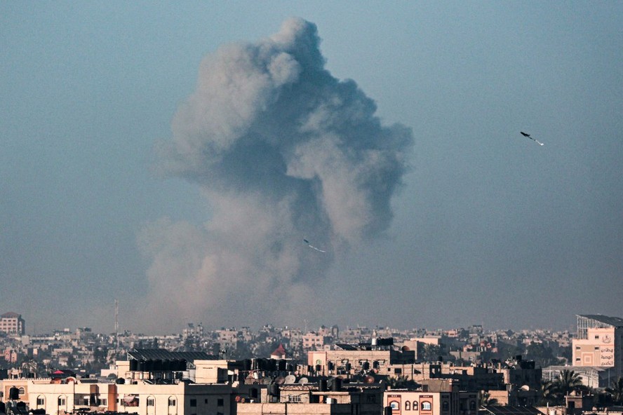 Foto tirada de Rafah mostra pipas empinadas no céu sobre cidade enquanto fumaça se espalha durante bombardeio israelense em Khan Yunis, no sul da Faixa de Gaza