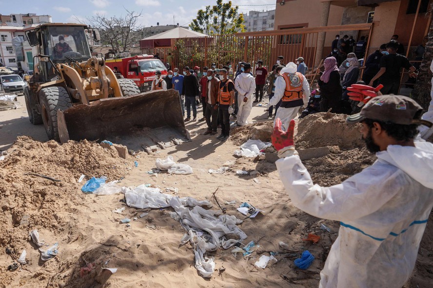 Profissionais de saúde palestinos procuram corpos enterrados no complexo do hospital Nasser em Khan Yunis, no sul da Faixa de Gaza.