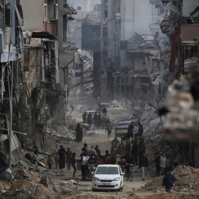 Palestinos caminham por entre escombros de prédios em Khan Younis, nesta segunda-feira, 8