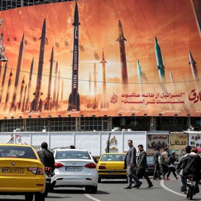 Motoristas passam por um outdoor que mostra mísseis balísticos iranianos, no centro de Teerã