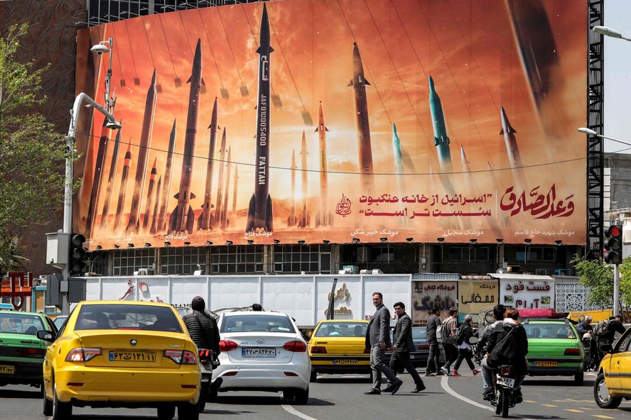 Motoristas passam por um outdoor que mostra mísseis balísticos iranianos, no centro de Teerã