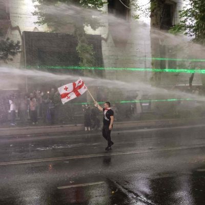 Manifestante ergue bandeira da Geórgia enquanto polícia atira jatos de água para dispersar ato
