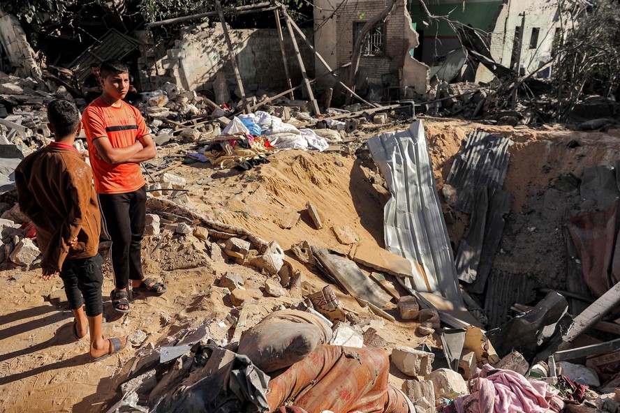 Crianças ao lado de cratera aberta por bombardeio israelense em Rafah