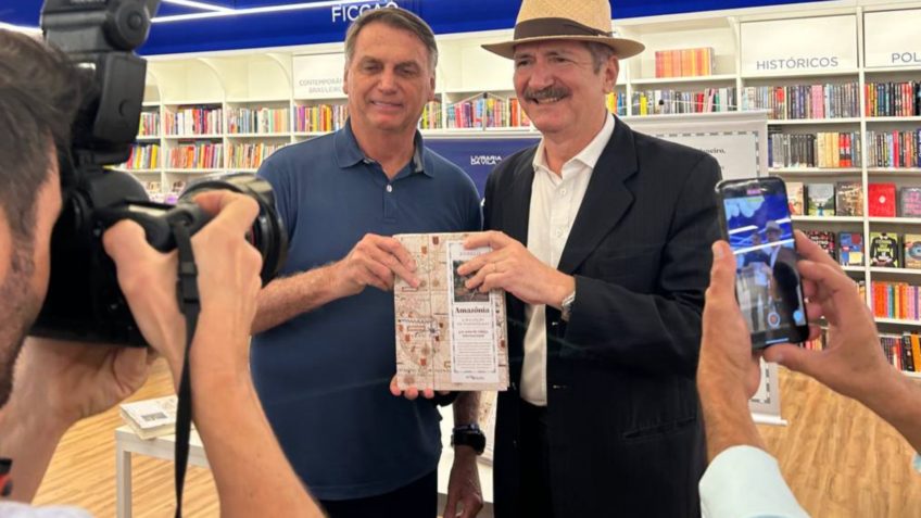 O ex-presidente Jair Bolsonaro (à esquerda, de azul) e o ex-ministro Aldo Rebelo (à direita, de chapéu) durante o lançamento do livro 