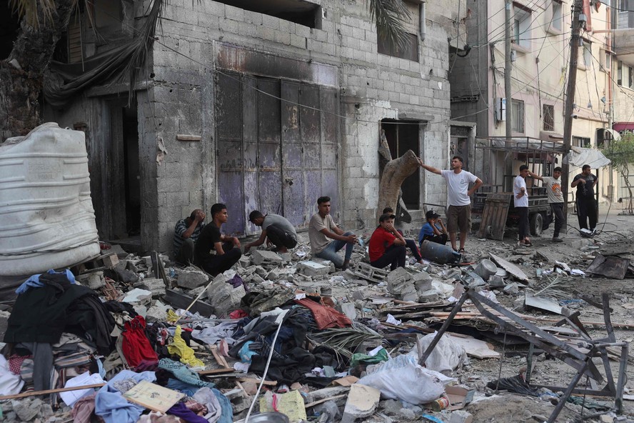 Situação humanitária em Rafah: palestinos sentam-se junto aos escombros de uma casa de família que foi atingida durante bombardeio