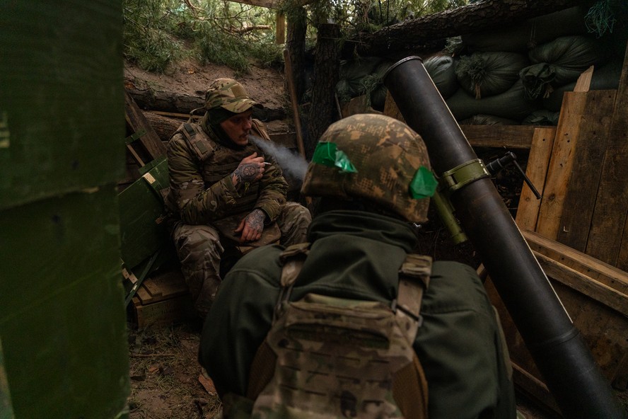 Soldados ucranianos aguardam ordens para disparar contra posições russas distantes apenas três quilômetros dali. Com a escassez de munições, os soldados passam horas e horas aguardando ordens para disparar. Foto tirada na Floresta de Kremina, Oblast de Donetsk, Ucrânia