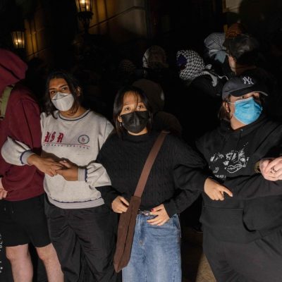 Estudantes/manifestantes cruzam os braços para proteger autoridades em potencial contra o alcance de colegas manifestantes que se barricaram dentro do Hamilton Hall,
