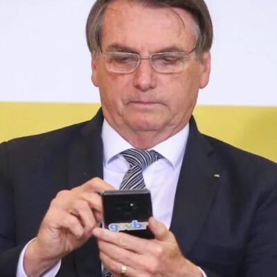 O presidente Jair Bolsonaro manuseia aparelho celular