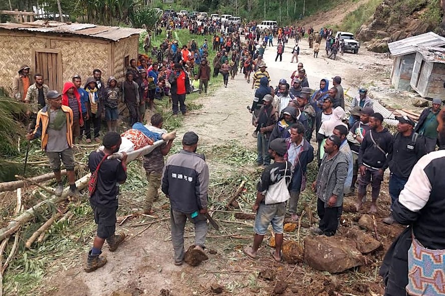 Moradores carregam uma pessoa em uma maca do local do deslizamento de terra até a vila de Yambali, na região de Maip Mulitaka, em Papua Nova Guiné.